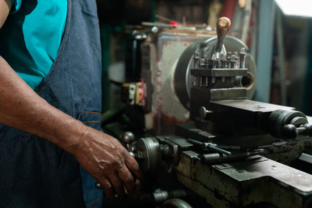 Close Up A senior Asian man preparing steel turning equipment. He is a small industrial steel turner...