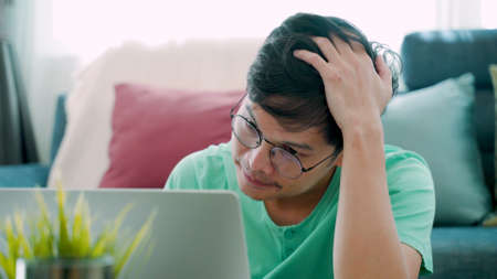 Close-up of facial expressions and gestures of a young Asian man, who is seriously stressed about his work.の写真素材