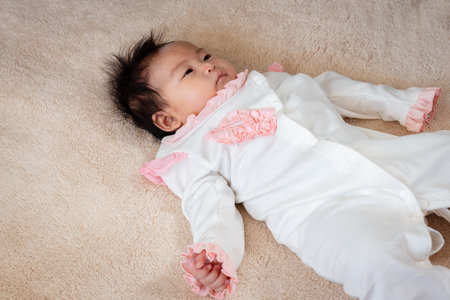 Close Up Portrait of a black-haired 3-month-old newborn playing in bed with a happy smile on her...