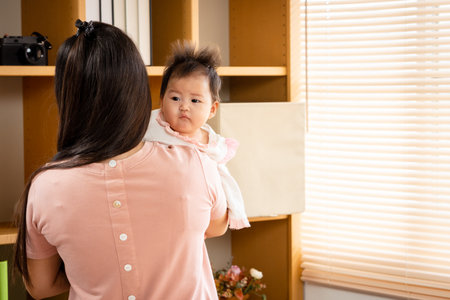 Close Up is a 3-month-old newborn Asian girl who her mother is holding. A single mother is holding her newborn baby by soothing her to sleep. in the bedroom of the house. Family and Healthy.の写真素材