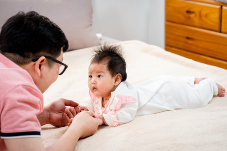 Slow, Asian father, wearing a pink shirt, Father lies, and plays with his daughter, Cherishingly, a...