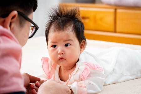 close-up Asian father, wearing a pink shirt, Father plays with his daughter gently, and cherishes...