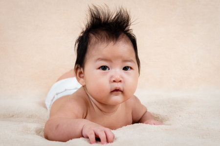 face close up, Asian newborn baby girl, lying prostrate in the bed,The child sleeps without clothes because the hot weather will make him uncomfortable, The little girl slept alone in a good mood.の写真素材