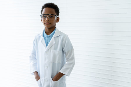 African little boy Standing with arms folded and smiling in the science classroom. In the front there is a table to put science test tubes. in elementary school, science experiments, chemistry,の写真素材