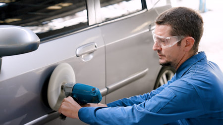Male mechanic wears work clothes in garage for work safety, wearing colored glasses sneak down on...