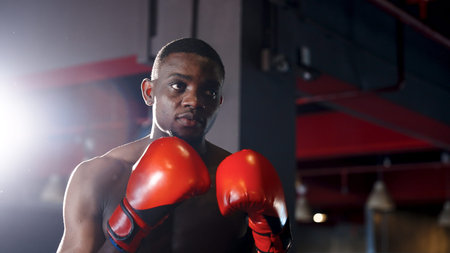 African boxer practicing boxing by punching his body back and forth for warm up on the boxing ring...