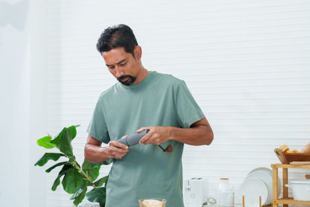 Asian man hand turning coffee bean grinder using coffee bean machine, ground make coffee powder before pouring coffee powder into drip machine drip-coffee drink in morning holiday.の写真素材