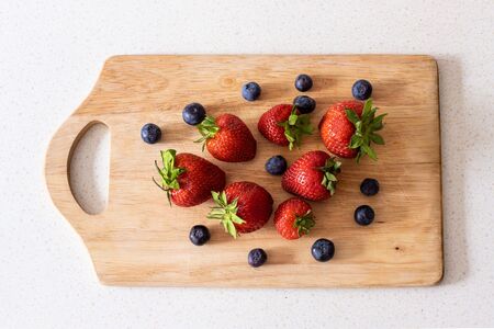 Juicy and fresh strawberries and blueberries on a wooden board.の写真素材