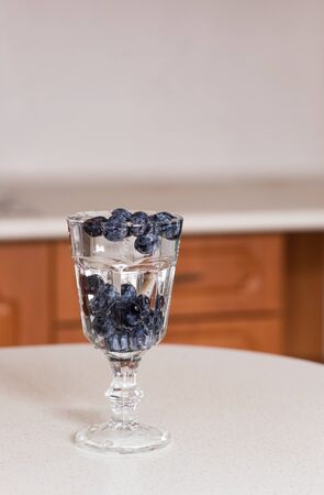 A glass of water and blueberries on the kitchen table. Beautiful air bubbles and fresh berries in the water.の写真素材