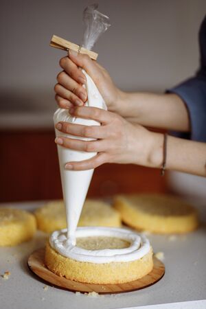 The process of making a cake. Applying the cream on the cake. Birthday or a wedding cake. Series.の写真素材
