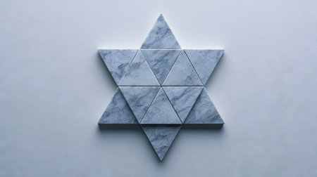 Star-shaped design is created using various triangular pieces of light gray and white marble. The pieces are arranged in a precise, geometric pattern, and are angled and interlocked to form the overall shape. The image is set against a plain, light gray background.の素材