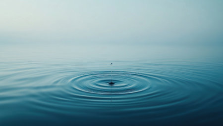 A single water droplet falling into the calm blue waters, creating ripples that spread out in an elegant pattern, symbolizing tranquility and reflection. The background is plain with no other elements to pepper it or appear on top of the surface, focusing all attention only on the drop's impact and its harmonious flow through the stillness of nature. --ar 53:30 --v 6.1 Job ID: ece52af9-f085-480e-bfe7-dfecfb3ca3e2の素材