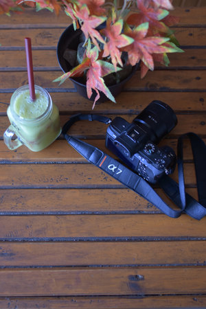 indonesia, 11-23-2020, sony a7 camera and nokia smartphone on a wooden table with a glass of fruit...