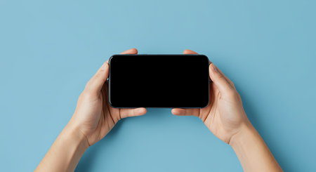 Female hands holding smartphone with blank screen on blue background, mockupの素材