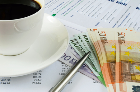 Office supplies with money and cup of coffee close up の写真素材