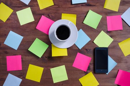 cup of coffee colored stickers, and smarfon on old wooden tableの写真素材