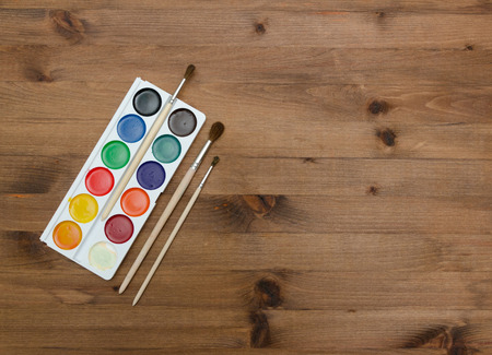 palette with paint and brushes on the wooden table backgroundの写真素材