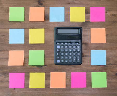 calculator and  multi colored stickers on old wooden table
