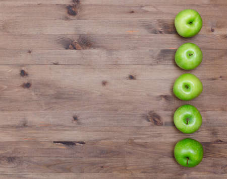 Several green apples in a row on old wooden tableの写真素材