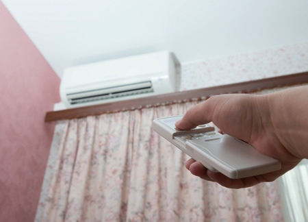 Hand with remote control directed on the air conditionerの写真素材