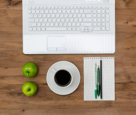 green apples on worplace with notebook, coffee  and pens  on old wooden table