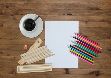 Paper sheet painting supplies and cup of coffee on old wooden table