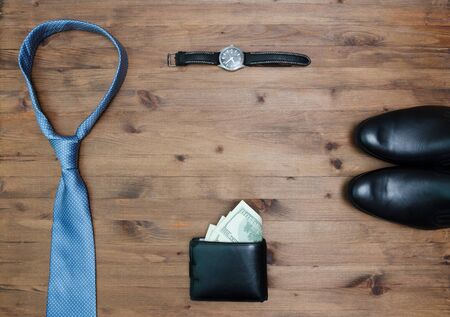 gentleman concept. tie dollars watches and shoes on  wooden table