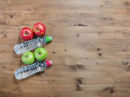Healthy lifestyle concept. colored Apples and sport water bottles on wooden tableの写真素材