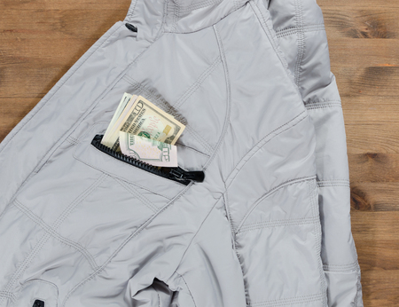 gentleman concept. jacket and dollars in the pocket on old wooden tableの写真素材