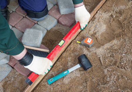 mason worker making sidewalk pavement with stone blocks