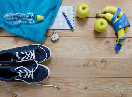 Fitness concept with sneakers. towel bottle of water measure tape fruit and a stopwatchの写真素材
