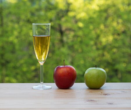 Wine glass red and green apples on table in the gardenの写真素材
