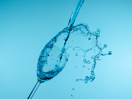 Glass with creative splashing water on blue backgroundの写真素材