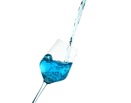 Creative splashing of blue water in the glass Isolated on whiteの写真素材