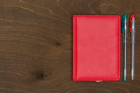 Red notebook and Colored gel pens on wooden background の写真素材