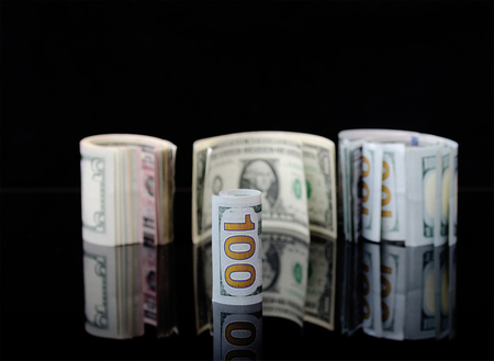 Dollar banknotes rolls on black background with reflection. Business concept.