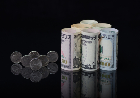 Dollar banknotes rolls and coins on black background with reflection. Business concept.