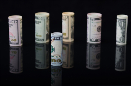 Dollar banknotes rolls on black background with reflection. Business concept.の写真素材