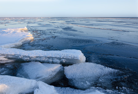 Melting pieces of thick ice on frozen sea at sunset timeの写真素材