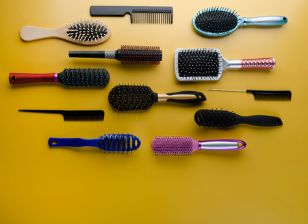 Various colored brushs and combs for hair on yellow background. Set of brush and hairbrush