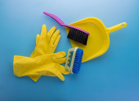Set for cleaning. Rubber gloves, brushes and scoop with a broom on blue background. Top view.の写真素材