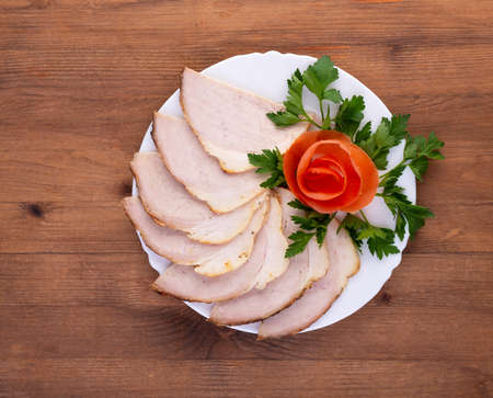 Pork ham sliced and decorated with parsley and tomato for holiday dinner buffet or appetizers set at old wooden table. Top angle view. Festive ham servingの写真素材