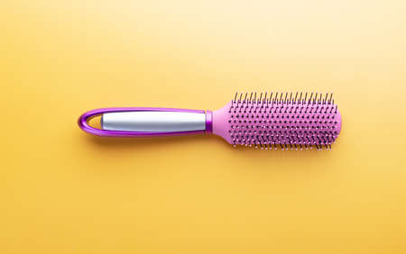 Hairstyle concept with hair brush on yellow background. Fashion, beauty and hygiene. Plastic comb for salon and home usageの写真素材