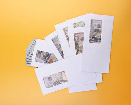 Pile of envelopes with dollar banknotes on yellowの写真素材