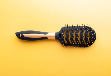 Hairstyle concept with hair brush on yellow background. Fashion, beauty and hygiene. Plastic comb...