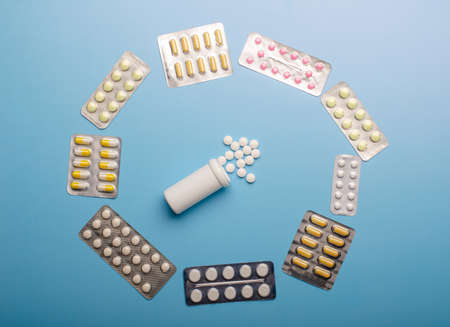 Colored Pills packed in blisters on blue background.