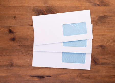 Blank envelopes with address window on wooden background. White paper envelopes mockup for business...