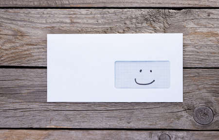 Envelope with emoticon icon in address window on wooden tableの写真素材