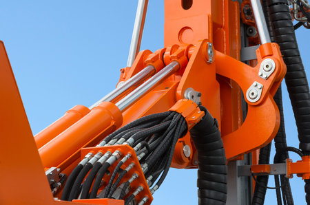 Detail of hydraulic bulldozer piston excavator arm against blue sky