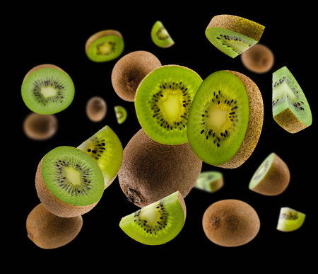 Perfectly retouched kiwis, whole halves and slices fly and levitate in space. isolated on blackの写真素材